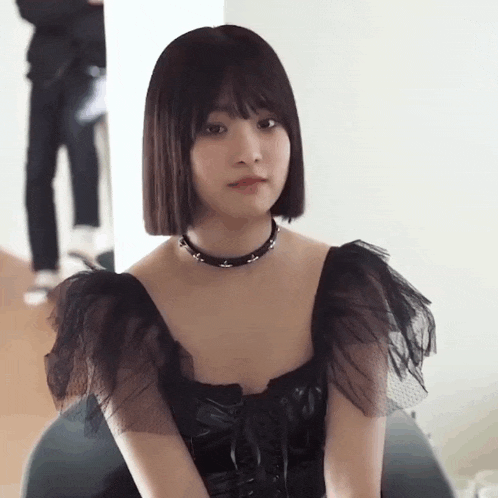 the girl is wearing a black dress and a choker .