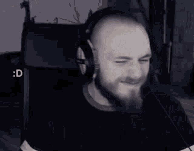 a man with a beard wearing headphones is smiling and waving .