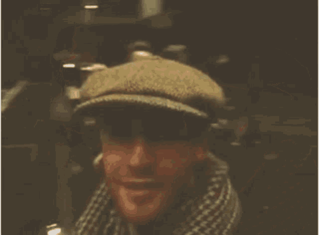 a man wearing a hat and scarf is smiling for the camera .