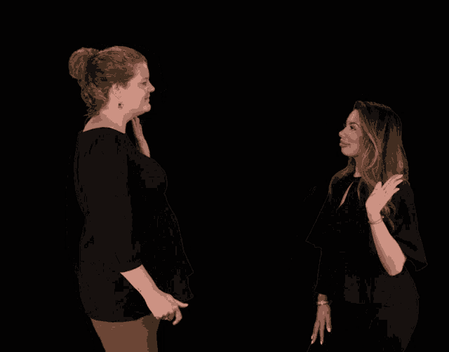 two women giving each other a high five in front of a black backdrop