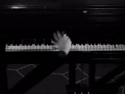 a black and white photo of a person playing a piano with a ring on their finger