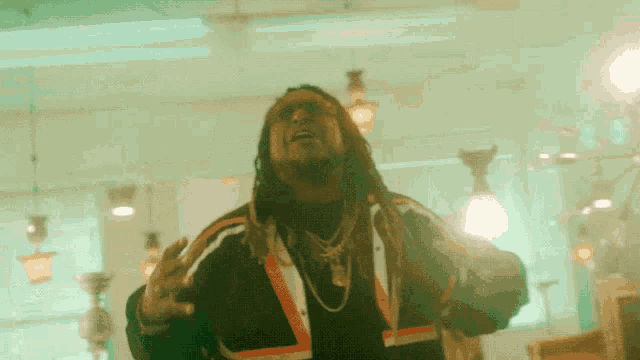 a man with dreadlocks is standing in a room with lots of lights hanging from the ceiling