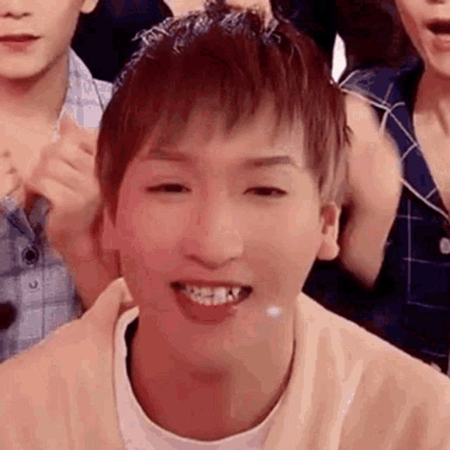 a close up of a young man smiling in front of a crowd .