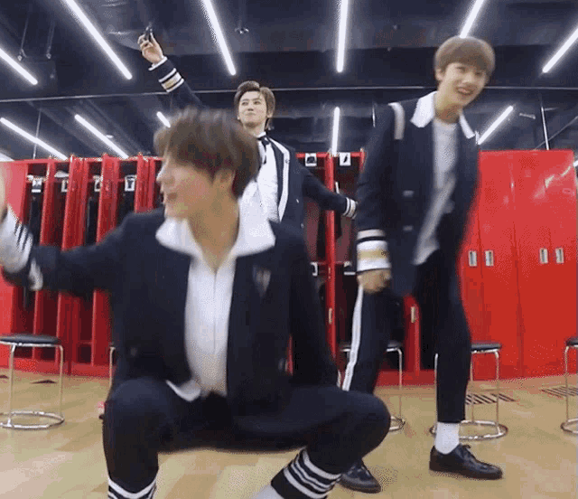 a group of young men are dancing in a locker room with the letter u in the background