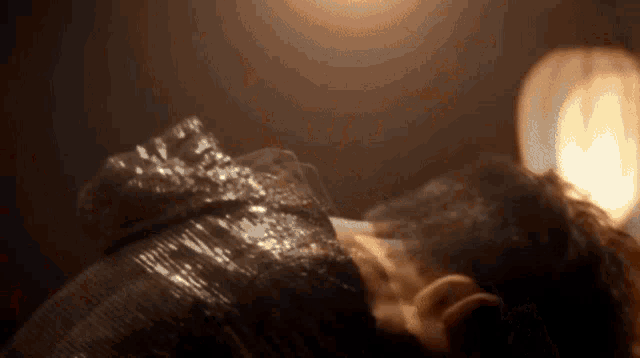 a close up of a person 's face in a dark room with a candle in the background .