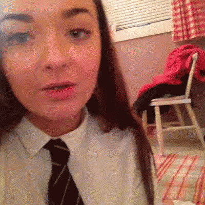 a woman wearing a white shirt and black tie is taking a selfie