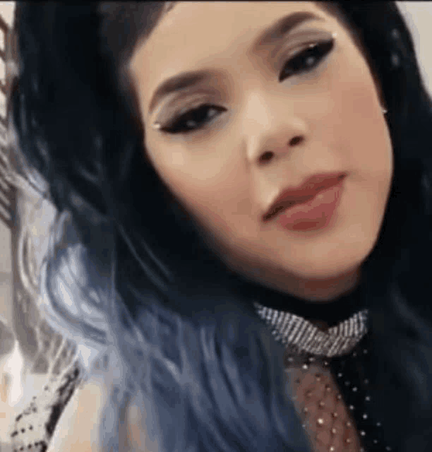 a close up of a woman with blue hair and a choker .