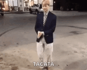 a man in a suit and tie is dancing in a gas station .