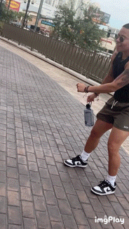 a person is standing on a brick sidewalk with a bottle of water in their hand