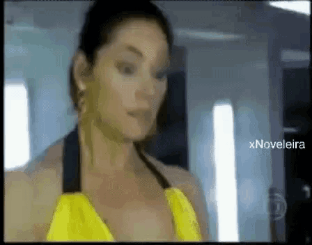 a woman in a yellow top is standing in front of a sign that says xnovelaira on it
