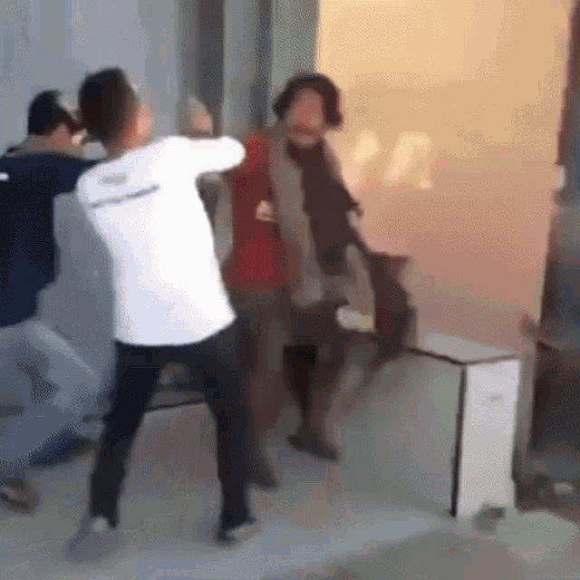 a group of people are fighting in a room with smoke coming out of it .
