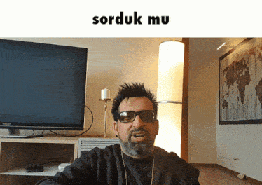 a man wearing sunglasses stands in front of a television and says " sorduk mu "