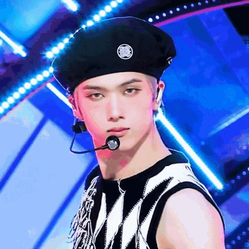 a young man wearing a black beret and a microphone on a stage