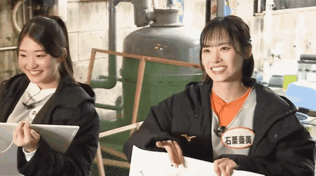 two girls are sitting next to each other and one has a name tag that says ' 石 葉 奏 美 '