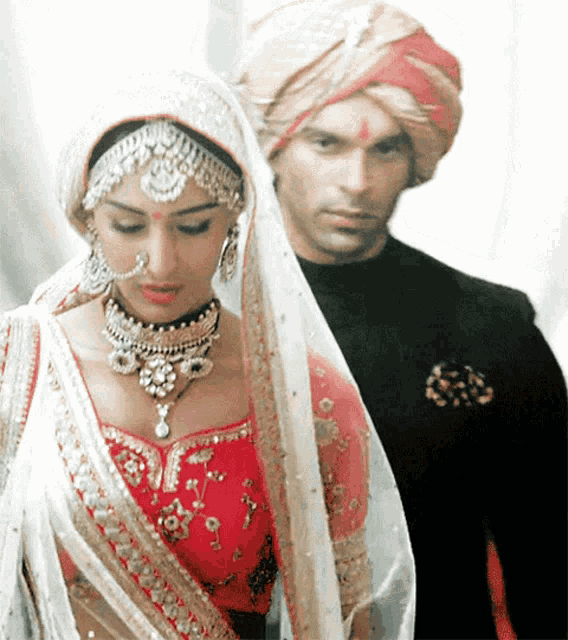 a bride and groom are standing next to each other wearing traditional indian clothing