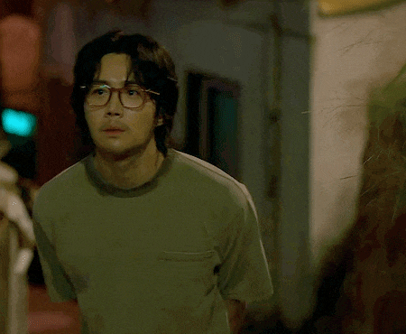 a man wearing glasses and a green shirt is looking at the camera