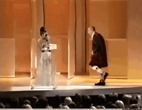 a man in a kilt is standing on a stage with a woman in a white dress