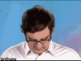 a man wearing glasses and a white shirt is looking down at something