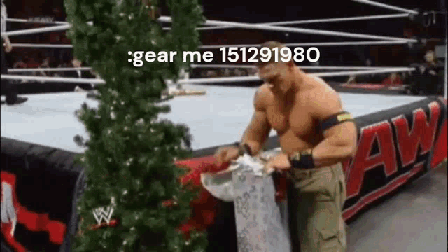 a man is standing in a wrestling ring next to a christmas tree and a sign .