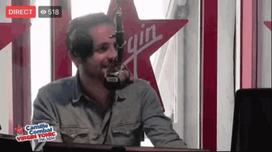 a man speaking into a microphone in front of a virgin star