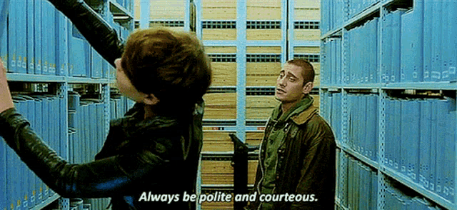two men are standing in a library and one of them is saying always be polite and courteous