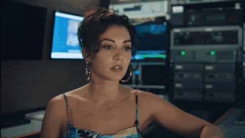 a woman wearing hoop earrings is sitting in front of a computer