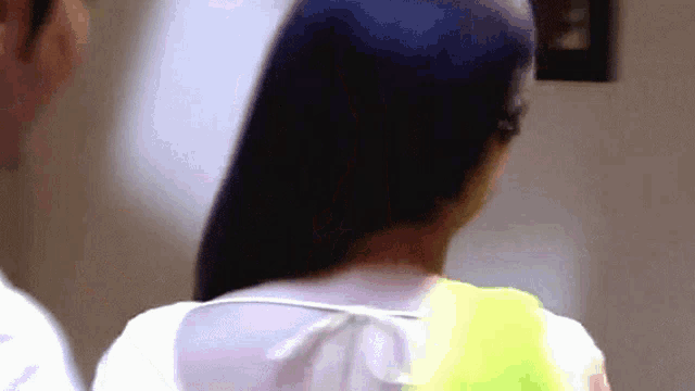 a woman 's back is shown in a blurry photo with a man in the background