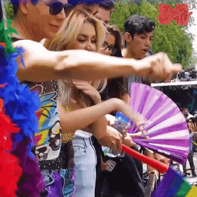 a group of people holding a purple fan with a rainbow flag behind them