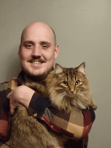 a man in a plaid shirt is holding a cat in his arms