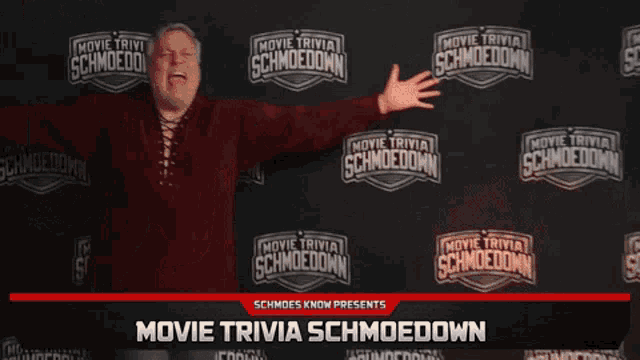 a man stands in front of a wall with movie trivia schmoedown written on it
