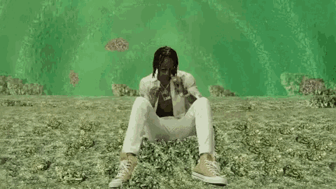a man is sitting on a pile of money and making a peace sign .