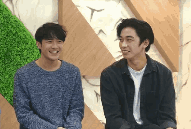two young men are sitting next to each other and smiling for the camera