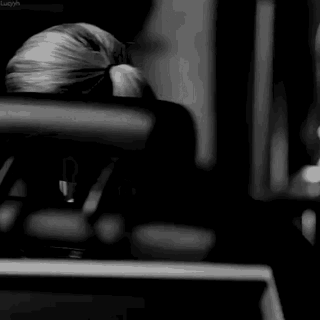 a black and white photo of a woman sitting in front of a computer .