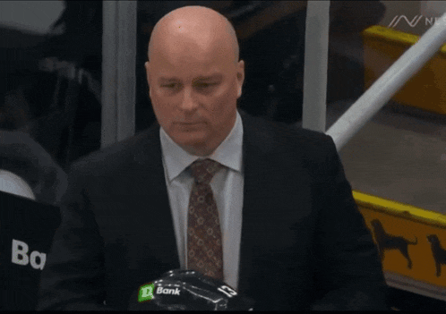 a man in a suit and tie holds a hockey helmet with a td bank logo on it