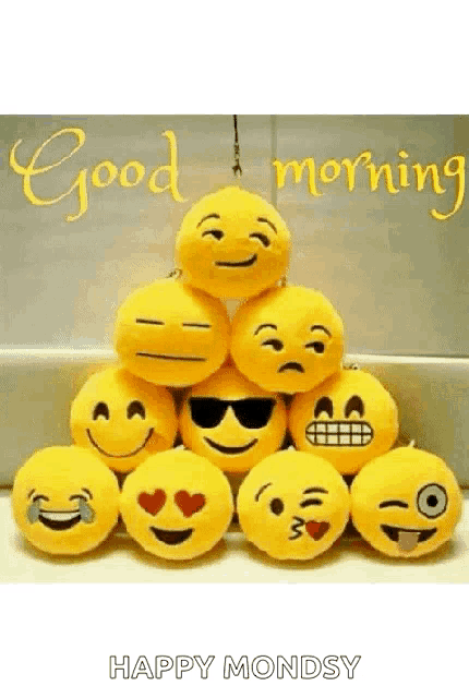 a bunch of stuffed smiley faces are stacked on top of each other and the words `` good morning happy monday '' .