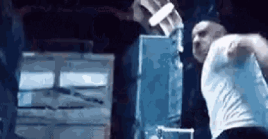 a man in a white shirt is standing in front of a machine that is cutting a piece of ice .