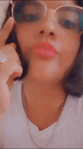a woman wearing glasses and a ring is making a face .