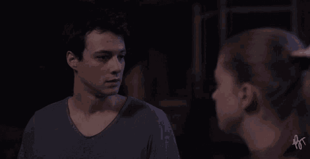 a man and a woman are looking at each other in a dark room with the letters ps on the bottom left