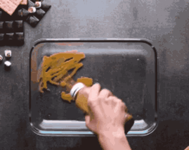 a person is pouring a sauce into a glass dish .