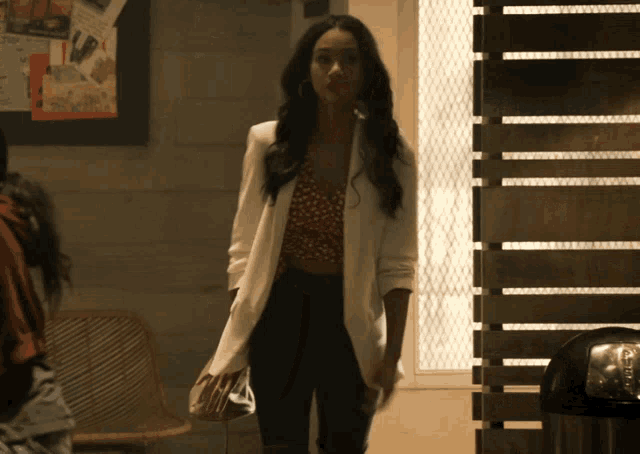 a woman wearing a white jacket and black pants