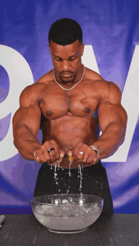 a shirtless man is cracking an egg into a bowl of liquid