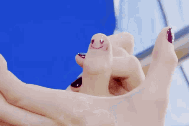 a woman with purple nails has a smiley face painted on her finger