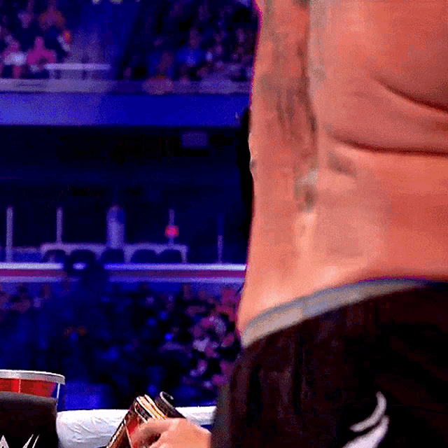 a man with a tattoo on his back is holding a can in his hand