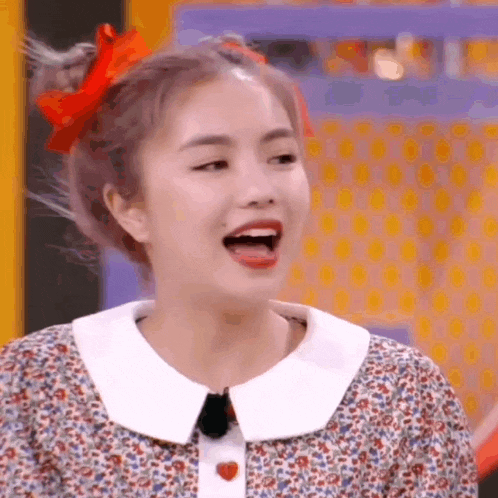 a woman with a red bow in her hair is making a funny face with her mouth open .