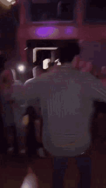 a group of people are dancing in a club while a man is squatting on the floor .