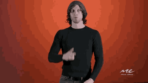a man wearing a black sweater and a beanie is pointing up