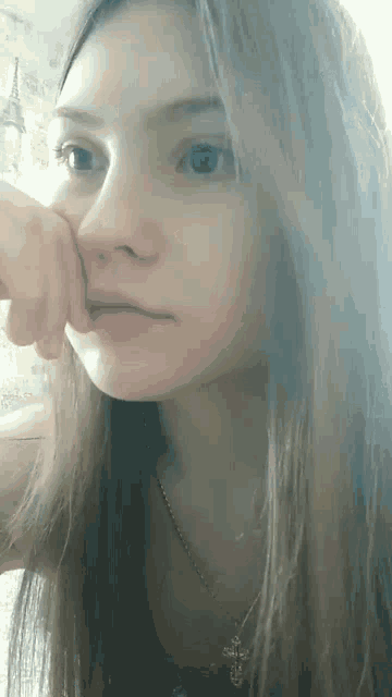 a close up of a girl 's face with a cross necklace