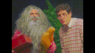 a man with glasses and a beard is standing next to a man in a santa costume