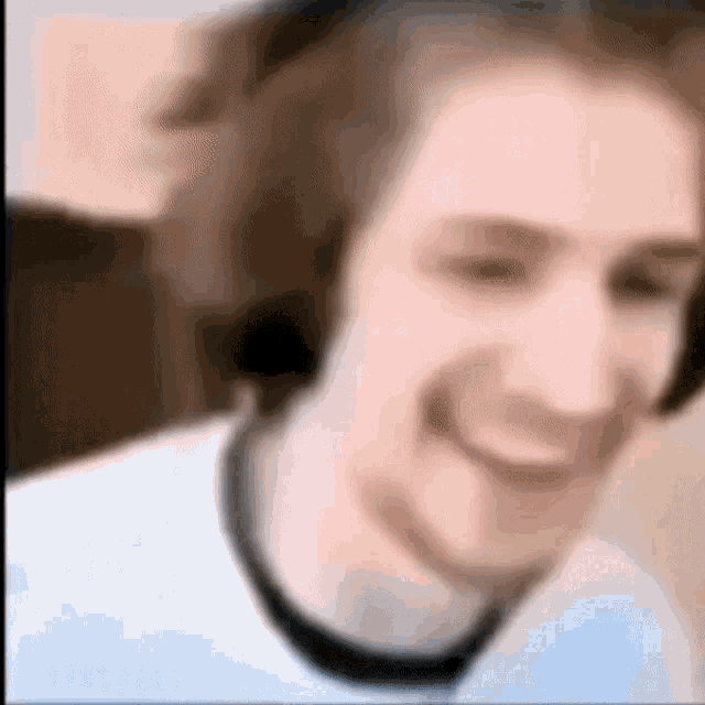 a man wearing headphones is smiling in a blurry photo .