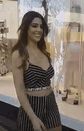 a woman in a striped top and shorts is standing in front of a mannequin .